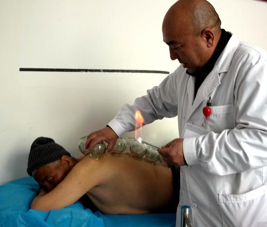 3月21日，家庭医生吐尔洪·依明在卫生室中医馆里为村民理疗。