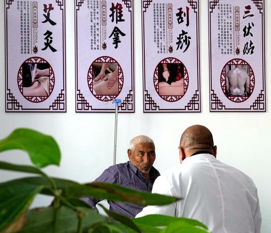 3月21日，家庭医生吐尔洪·依明在卫生室中医馆里为村民理疗。