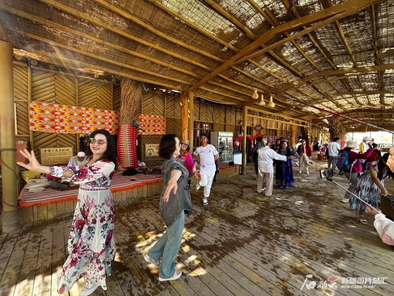 5月3日，在罗布人村寨景区，游客们和演员互动学习跳舞。石榴云/新疆日报记者 张小宓摄