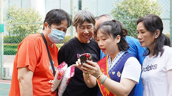 图为工作人员在为老年人演示智能手机基础操作。罗鹏 摄