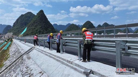 图为岳圩高速建设者正在安装波形钢护栏。戴肖玲 供图