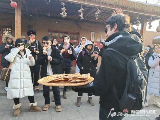 1月15日,代表团成员在库车大馕小巷品尝馕。陆雪婷 摄