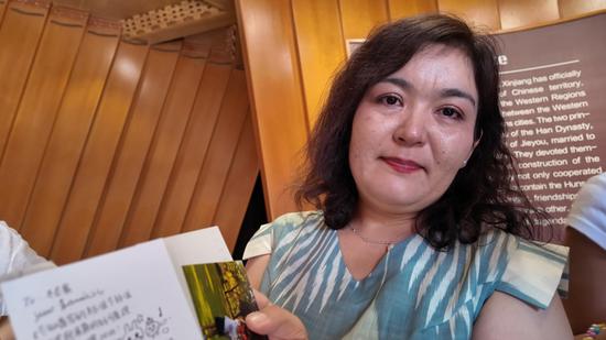 穆凯代斯・阿不都黑力力展示南京青少年郑佳乐送给女儿木尼赛・居来提的礼物