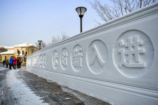新疆乌鲁木齐市风景社区居民在一小区内参观十九大主题雪雕墙。