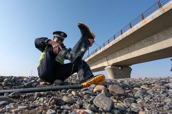 流水,民警们趟过小河后倒出靴子里的水,擦拭干