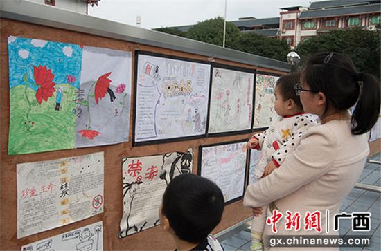 一位母亲与孩子一起观看禁毒宣传手抄报。 一位母亲与孩子一起观看禁毒宣传手抄报。