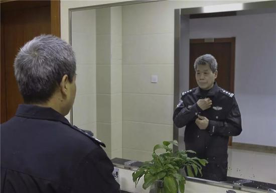 图为:方良明对着镜子仔细地整理警服 刘冰菲 摄