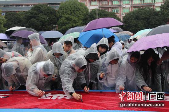 学生雨中坚持拒毒签名。陶云 摄 学生雨中坚持拒毒签名。陶云 摄