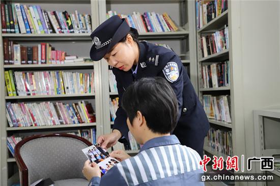 蒋春利将监区警察走访慰问其家的照片给罪犯看。颜小芳 摄 蒋春利将监区警察走访慰问其家的照片给罪犯看。颜小芳 摄