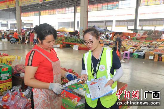 图为工作人员向经营户发放宣传材料。 图为工作人员向经营户发放宣传材料。
