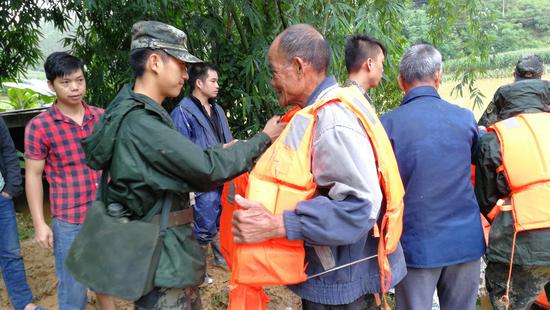 圖為武警官兵正在為老人穿上救生衣。 圖為武警官兵正在為老人穿上救生衣。