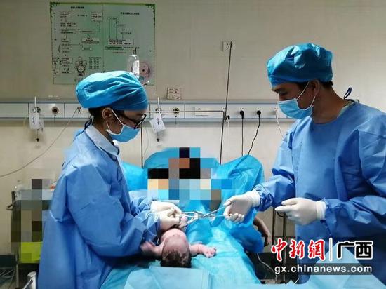 图为一位陪伴妻子分娩的男士，在助产士的指导为孩子亲自剪断脐带。