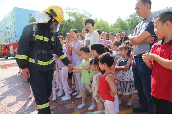 图为消防员与孩子们互动。