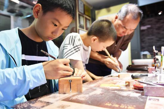 图为:小学员在学习篆刻 王刚 摄