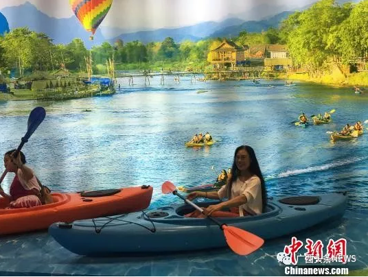 资料图：在老挝“魅力之城”展区，市民坐在小船上划桨，仿佛穿越到了风景宜人的万象省。　陈秋霞　摄