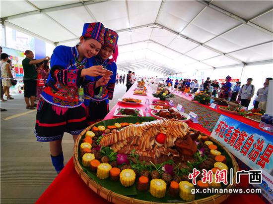 被毛南山乡精美菜品吸引的壮乡少女在拍照。 被毛南山乡精美菜品吸引的壮乡少女在拍照。