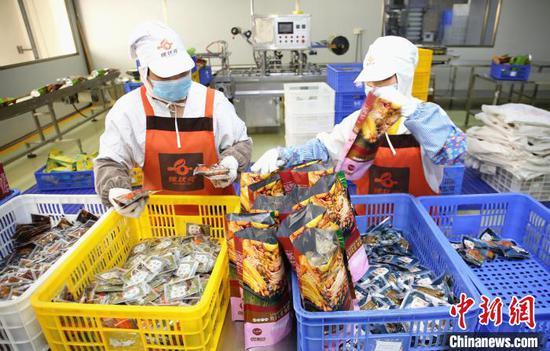 广西螺状元食品科技股份有限公司包装车间,工人正在将配料装入袋内。 朱柳融 摄 广西螺状元食品科技股份有限公司包装车间,工人正在将配料装入袋内。 朱柳融 摄