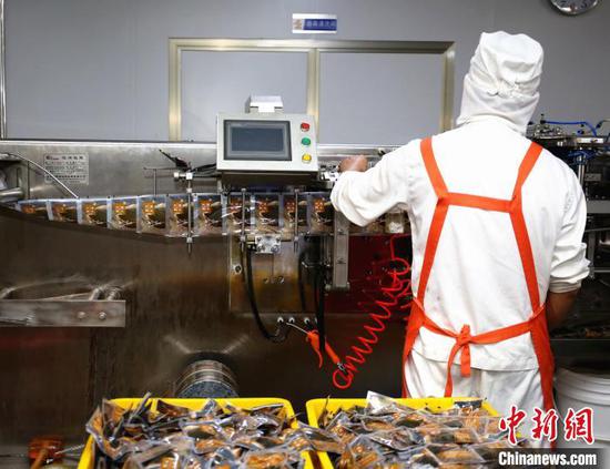 广西螺状元食品科技股份有限公司生产线,工人正在汤料包装设备旁工作。 朱柳融 摄 广西螺状元食品科技股份有限公司生产线,工人正在汤料包装设备旁工作。 朱柳融 摄