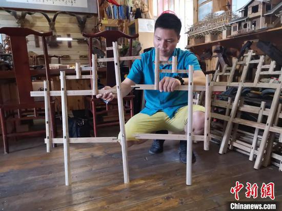 杨云东展示侗族木构建筑模型,木块之间无需钉子连接。 林馨 摄 杨云东展示侗族木构建筑模型,木块之间无需钉子连接。 林馨 摄