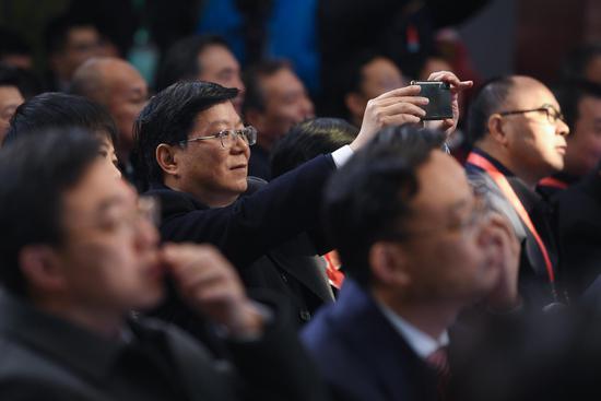 图为：现场嘉宾在听会期间拍照。王刚 摄