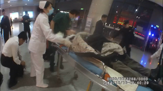 图为众人合力将晕倒旅客送往医院。 图为众人合力将晕倒旅客送往医院。