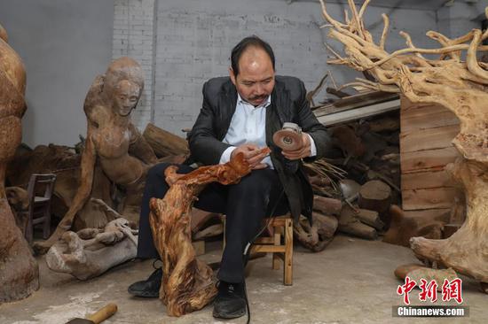 刘德付在工艺厂内打磨木雕作品。中新社记者 瞿宏伦 摄 刘德付在工艺厂内打磨木雕作品。中新社记者 瞿宏伦 摄