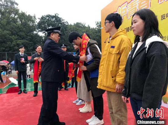 出席启动仪式的嘉宾给外卖小哥及学生代表授“反诈使者”绶带。 蒋雪林 摄 出席启动仪式的嘉宾给外卖小哥及学生代表授“反诈使者”绶带。 蒋雪林 摄