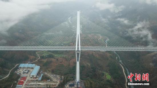 12月30日，贵州平塘，世界第一混凝土高塔桥——平塘特大桥宣布建成通车，历时3年建设的贵州省平塘至罗甸高速公路也将全线贯通。据悉，平罗高速于2016年4月开工建设，平塘特大桥是其重大控制性工程，该桥全长2135米，是一座三塔双索面叠合梁斜拉桥，其中，16号“钻石形”主塔高达332米，相当于110层楼高，是目前世界最高钢筋混凝土桥塔。图为航拍平塘特大桥。中新社记者 瞿宏伦 摄