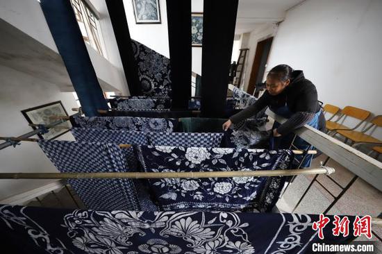 贵州丹寨宁航蜡染传承基地,一名工人在晾晒染好的蜡染床单。 黄晓海 摄 贵州丹寨宁航蜡染传承基地,一名工人在晾晒染好的蜡染床单。 黄晓海 摄