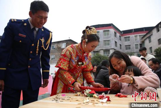 新郎與新娘給參加集體婚禮的親友們發喜糖。 黃曉海 攝