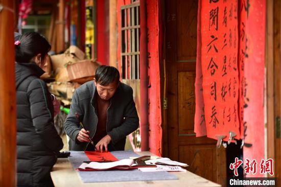 图为商家在集市上写春联售卖。 杨武魁 摄 图为商家在集市上写春联售卖。 杨武魁 摄