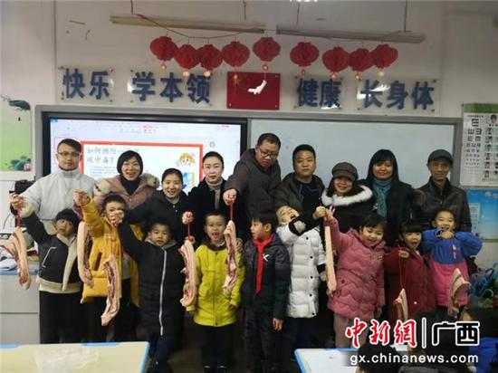图为桂林市芦笛小学一年级一班期末获奖2斤猪肉的9名同学与家长们合影。 以琴 摄