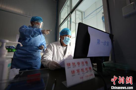 图为李斌(白衣者)向值班医生了解接诊情况。 黄晓海 摄 图为李斌(白衣者)向值班医生了解接诊情况。 黄晓海 摄