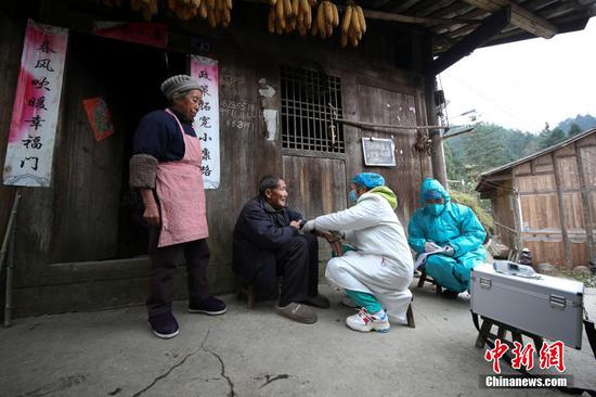 图为1月31日,肖世军(蓝衣)、潘启兰在为村民巡诊。 中新社发 黄晓海 摄 图为1月31日,肖世军(蓝衣)、潘启兰在为村民巡诊。 中新社发 黄晓海 摄