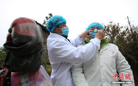 图为在贵州丹寨排调镇党早村宰飞自然寨,肖世军(左)在整理潘启兰的防护口罩。 黄晓海 摄 图为在贵州丹寨排调镇党早村宰飞自然寨,肖世军(左)在整理潘启兰的防护口罩。 黄晓海 摄