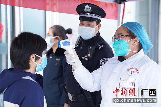 图为黄贵国夫妻一起给出站旅客测量体温。