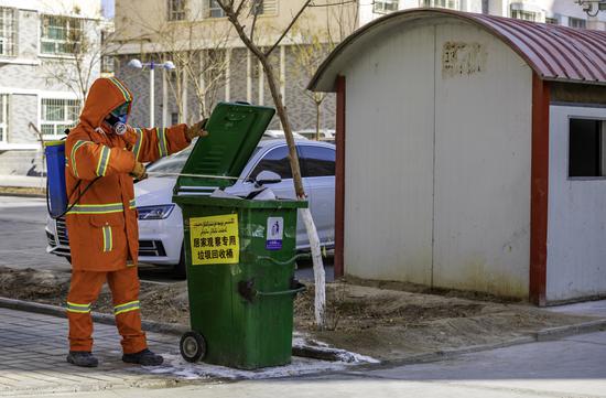 环卫工人对垃圾桶进行消毒。李飞摄
