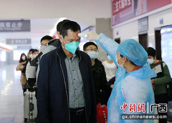 2月11日,在钦州火车东站出站口,医务人员对出站旅客检测体温。曾开宏 摄 2月11日,在钦州火车东站出站口,医务人员对出站旅客检测体温。曾开宏 摄