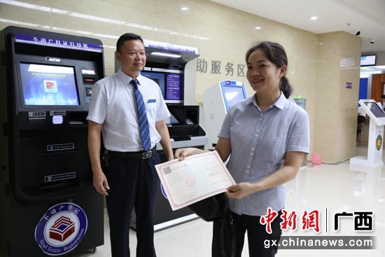 广西在全国率先实现不动产登记 “网上办理”“不见面审批”,为疫情防控期间便民利民创造了条件。图为业主在登记机构领取不动产权证书。黄尚宁 摄 广西在全国率先实现不动产登记 “网上办理”“不见面审批”,为疫情防控期间便民利民创造了条件。图为业主在登记机构领取不动产权证书。黄尚宁 摄
