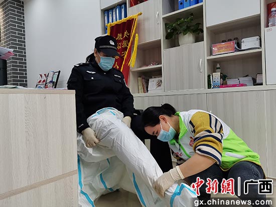社区工作人员协助范丽萍穿防护服。
