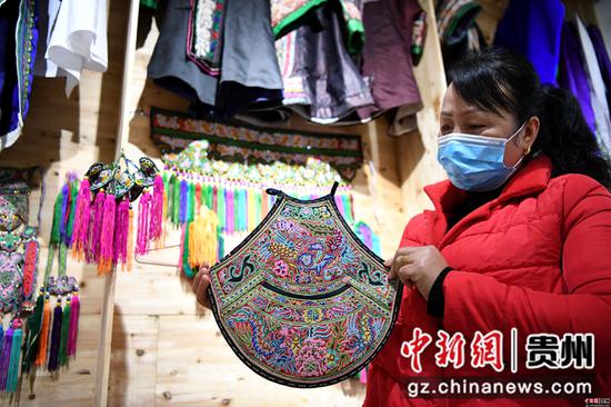 3月18日,在贵州省榕江县卧龙移民安置小区,一妇女在扶贫车间里展示自己的刺绣作品。 3月18日,在贵州省榕江县卧龙移民安置小区,一妇女在扶贫车间里展示自己的刺绣作品。