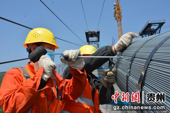 施工人员正在对主缆出现的夹丝进行调整。 施工人员正在对主缆出现的夹丝进行调整。