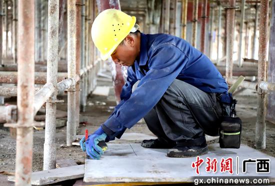 在融水人民医院妇产科综合楼建筑工地现场，蒙成峰正在作业。
