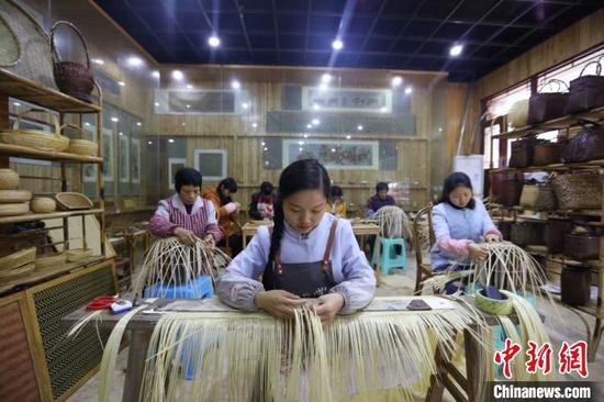 图为杨昌芹带领手工艺人们加紧编制竹工艺品。 王长育 摄 图为杨昌芹带领手工艺人们加紧编制竹工艺品。 王长育 摄