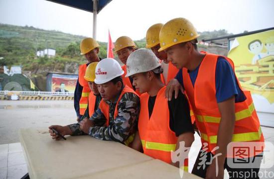 5月21日，贵州贵阳，一处建筑工地上的施工人员通过手机直播观看开幕会。当日，全国政协十三届三次会议在北京人民大会堂开幕。
中新社记者 瞿宏伦 摄