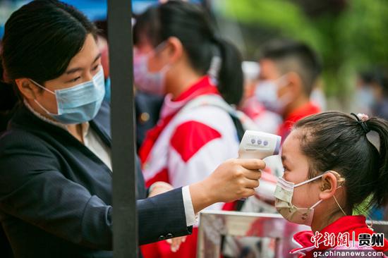 5月27日，贵州省毕节市实验学校的学生在进入学校前进行体温测量。