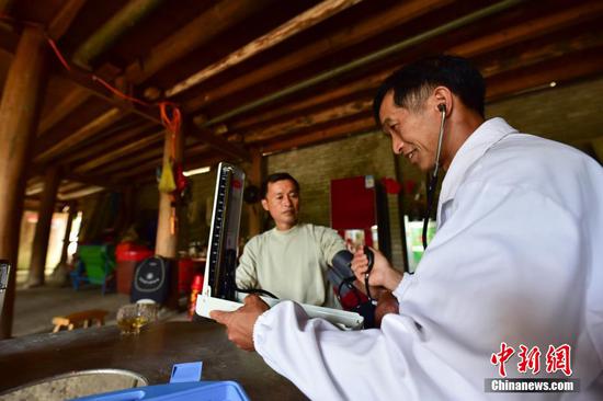 龙光庆(右)为村民杨胜良测量血压。 杨武魁 摄 龙光庆(右)为村民杨胜良测量血压。 杨武魁 摄