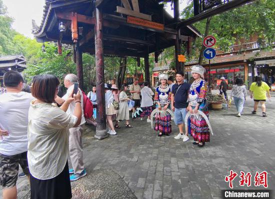 游客在西江千户苗寨景区内与穿着苗族服饰的少女合影留念。 岳旺 摄 游客在西江千户苗寨景区内与穿着苗族服饰的少女合影留念。 岳旺 摄