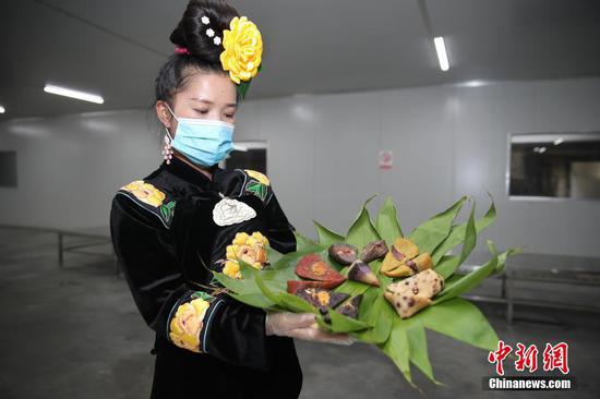6月25日,工人展示各种特色粽子。当日是端午节,贵州省黔东南苗族侗族自治州台江县排羊乡哆蝶食品加工厂内,20余名工人正在赶制当地特色的“五彩粽”,满足市场需求。五彩粽是当地百姓就地取材,把不同植物分别捣成黑、紫、黄、红四种颜色的汤汁,再用汤汁把糯米上色,与白色的糯米一起用粽叶包制而成。五彩粽色彩艳丽、香软可口,受到当地百姓和游客的喜爱。 中新社记者 瞿宏伦 摄 6月25日,工人展示各种特色粽子。当日是端午节,贵州省黔东南苗族侗族自治州台江县排羊乡哆蝶食品加工厂内,20余名工人正在赶制当地特色的“五彩粽”,满足市场需求。五彩粽是当地百姓就地取材,把不同植物分别捣成黑、紫、黄、红四种颜色的汤汁,再用汤汁把糯米上色,与白色的糯米一起用粽叶包制而成。五彩粽色彩艳丽、香软可口,受到当地百姓和游客的喜爱。 中新社记者 瞿宏伦 摄