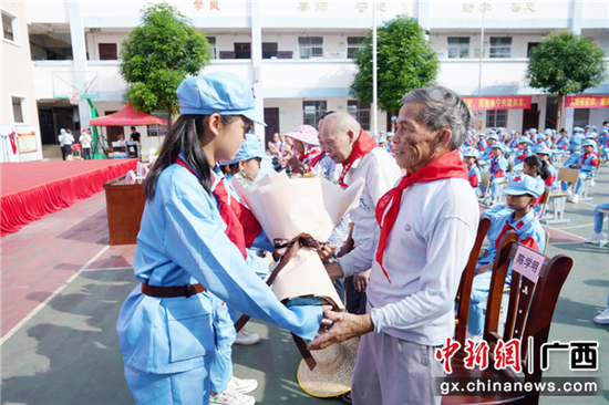 新兰小学少先队员代表为出席本次活动的嘉宾佩戴红领巾、赠送鲜花 广西革命纪念馆爱国爱党宣传教育活动走进村级小学